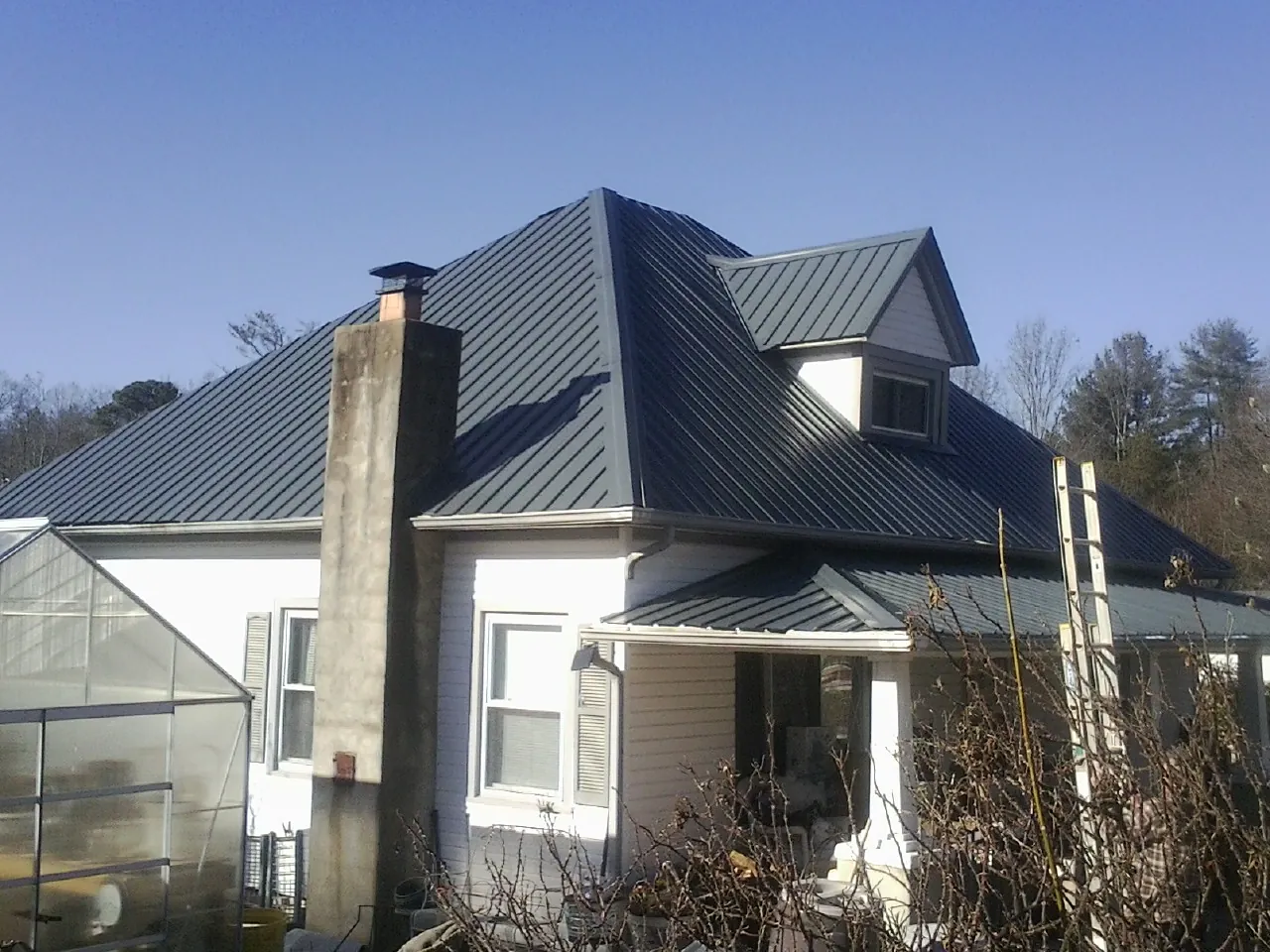 Dark blue standing seam metal roof on a white farmhouse with dormer — Slate & Tile Roof Repair by Roofing Brothers in Lemon Grove