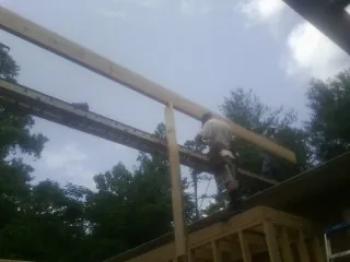 Carpenter setting a ridge beam over a new addition frame — Ice Dam Removal by Roofing Brothers in Lemon Grove