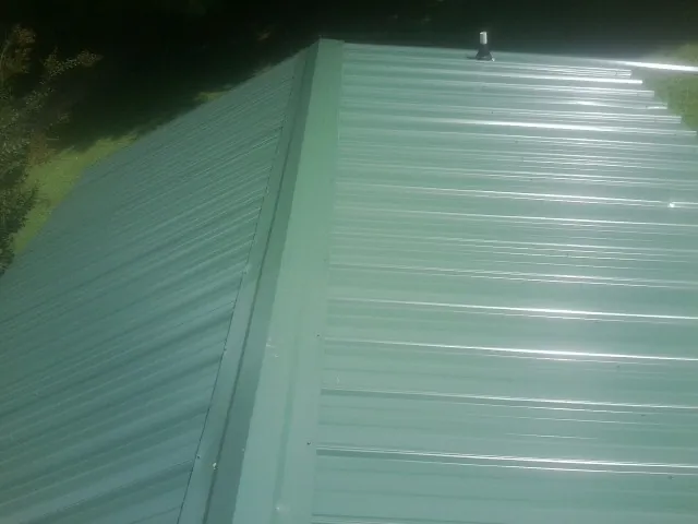 New green metal panels meeting at the ridge of a roof — Flat Roof Repair work by our crew in Lemon Grove