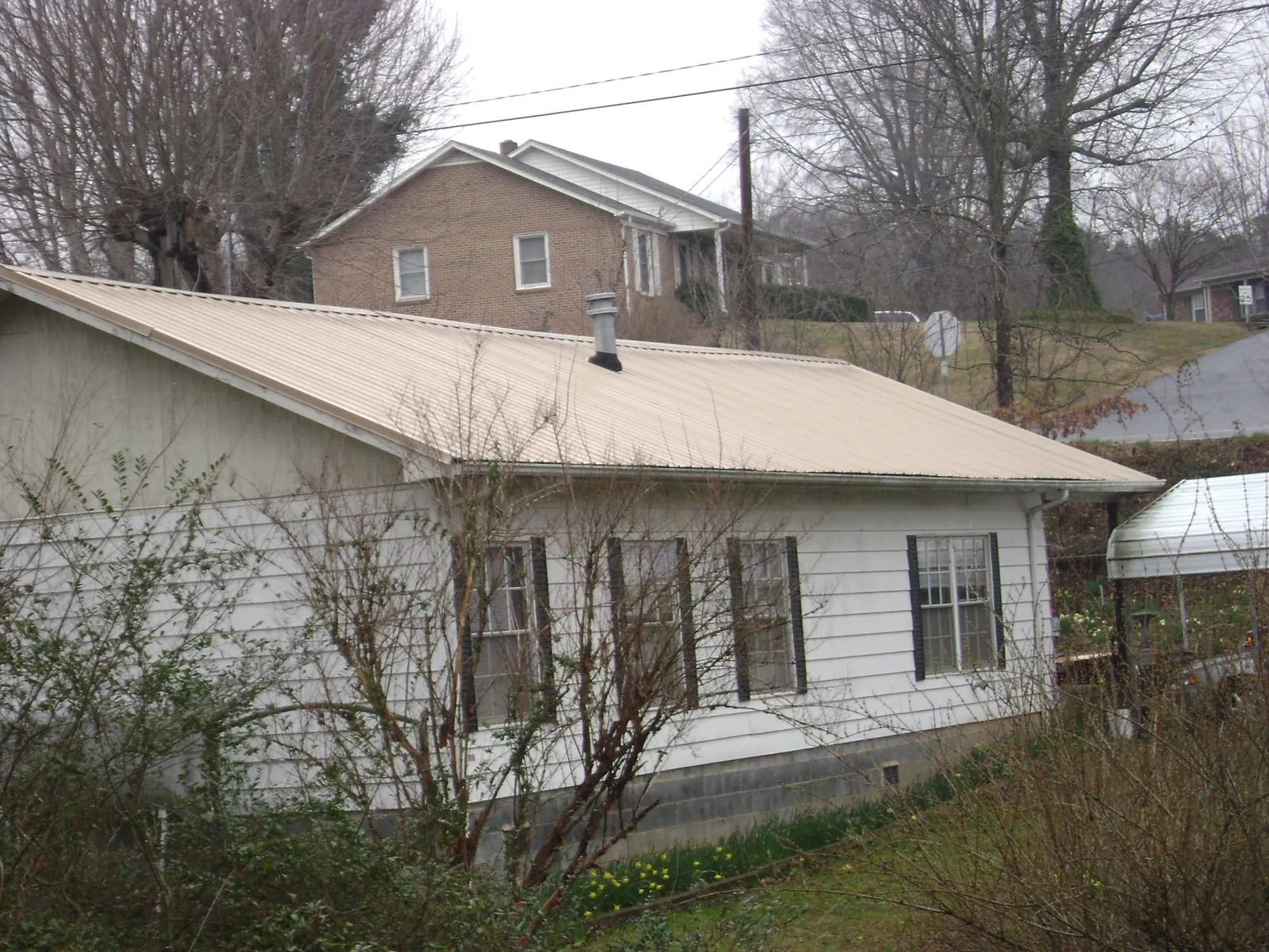 Tan metal roof on a white sided house set into a hillside — Commercial Roofing by Roofing Brothers in Lemon Grove