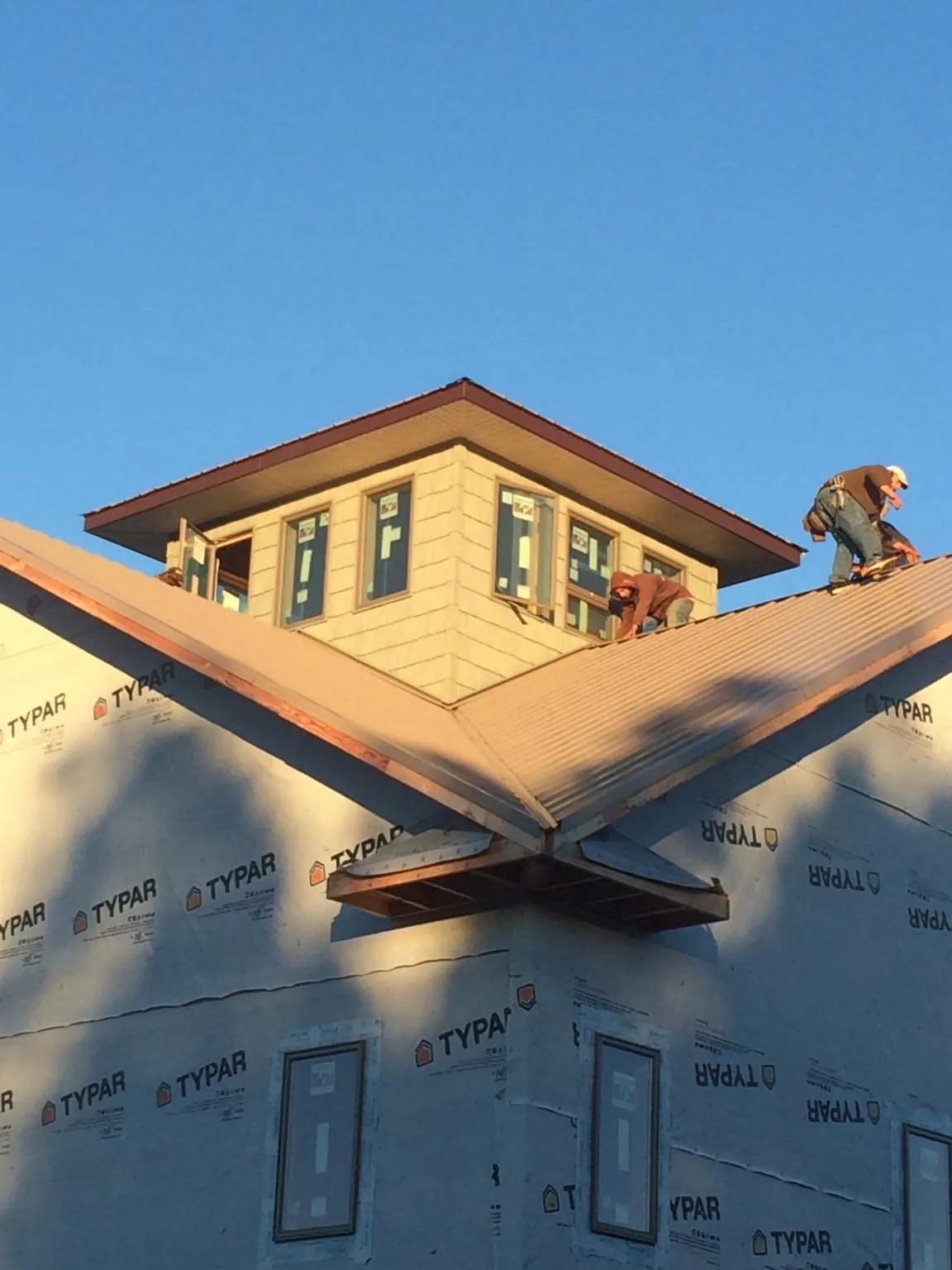 Roofers working around a rooftop cupola on a new metal roof at sunset — Roof Waterproofing in Lemon Grove by Roofing Brothers